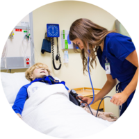 A nursing student practices checking blood pressure on a practice dummy.